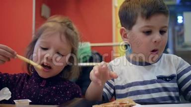 为小女孩和男孩准备的带有酱汁的<strong>法式炸薯条</strong>，男孩子咀嚼汉堡包，有趣的孩子在快餐中玩耍